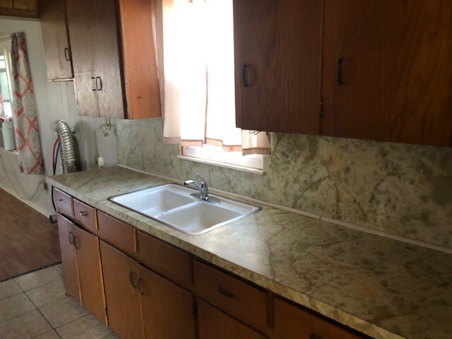 kitchen featuring tasteful backsplash, sink, and light tile patterned floors