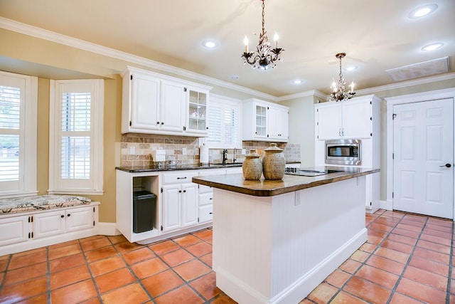5413 Bent Oak Ct, San Angelo, TX 76904 - kitchen with a chandelier, stainless steel microwave, dark countertops, backsplash, and crown molding