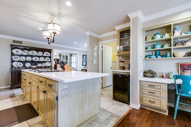 kitchen with ornamental molding, a kitchen island with sink, sink, and wine cooler