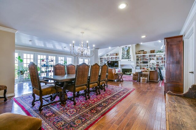 dining space featuring crown molding, vaulted ceiling, wood-type flooring, and a notable chandelier