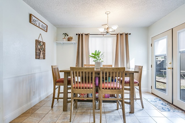 dining area featuring french doors, a textured ceiling, and light tile patterned floors