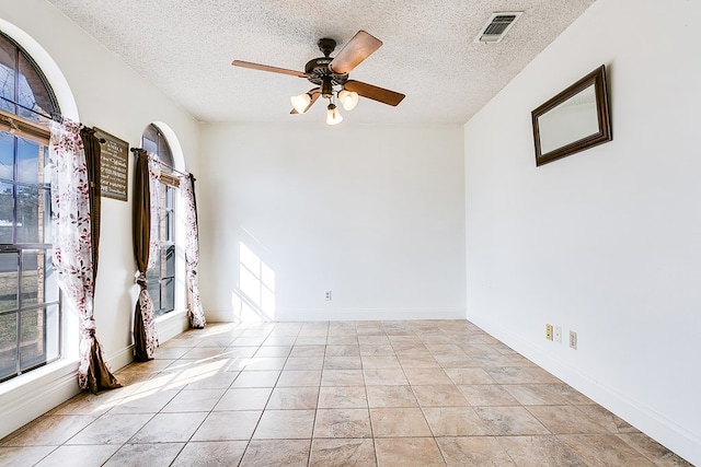 empty room featuring light tile patterned flooring, ceiling fan, and a textured ceiling