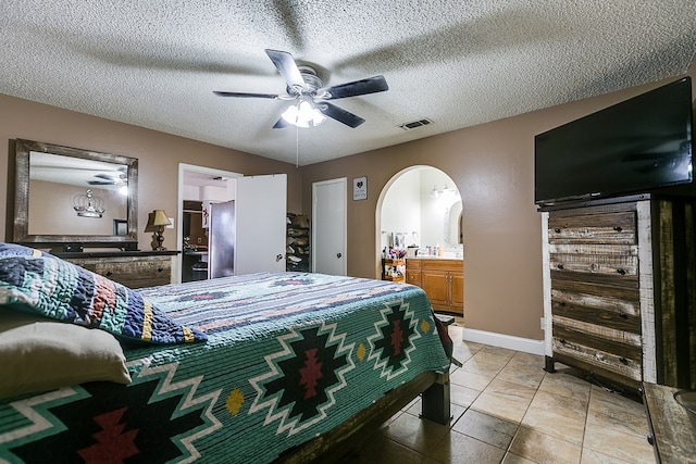 bedroom featuring connected bathroom, a textured ceiling, ceiling fan, and light tile patterned flooring