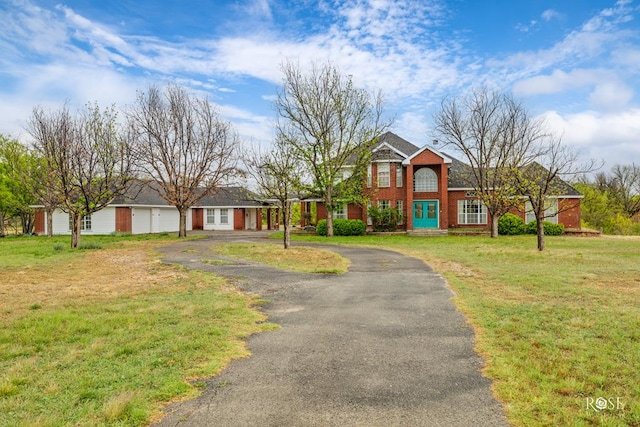 view of front of home featuring brick siding, aphalt driveway, a front yard, and a garage