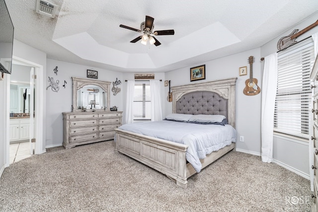 bedroom with carpet flooring, a textured ceiling, a tray ceiling, and ceiling fan