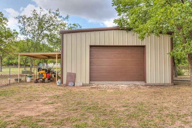 garage featuring a garage, driveway, and fence