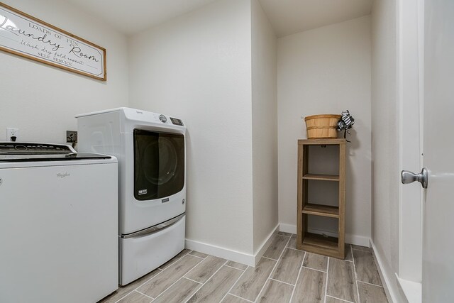 clothes washing area featuring laundry area, wood tiled floor, baseboards, and washer and clothes dryer