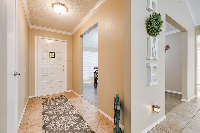 foyer featuring light tile patterned floors, ornamental molding, and a textured ceiling