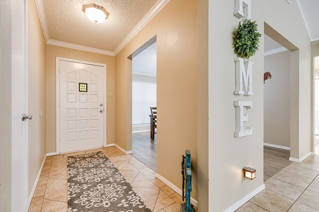 entrance foyer with a textured ceiling, ornamental molding, and light tile patterned flooring