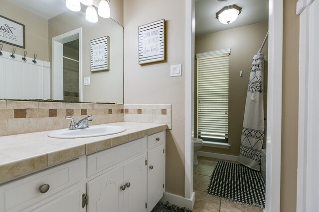 bathroom featuring vanity, tile patterned flooring, tasteful backsplash, and toilet