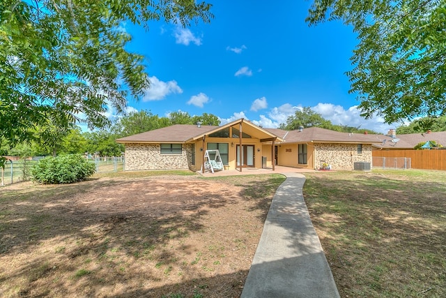 ranch-style home with a front yard, fence, and central air condition unit