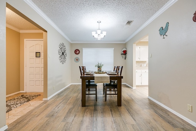 dining area featuring ornamental molding, wood-type flooring, an inviting chandelier, and a textured ceiling