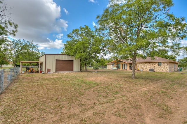 view of yard featuring a garage, driveway, fence, cooling unit, and an outdoor structure