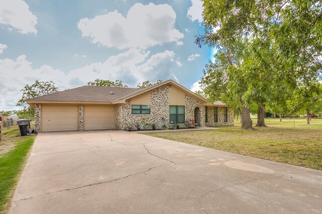 ranch-style house featuring stone siding, an attached garage, driveway, and a front lawn