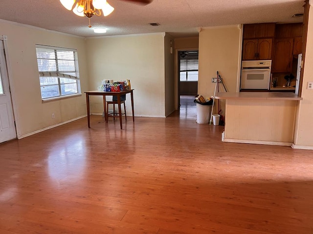 interior space featuring crown molding, wood-type flooring, a textured ceiling, ceiling fan, and white oven