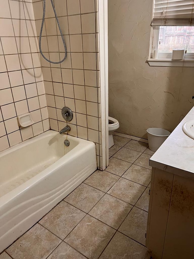 full bathroom featuring tiled shower / bath, vanity, toilet, and tile patterned flooring