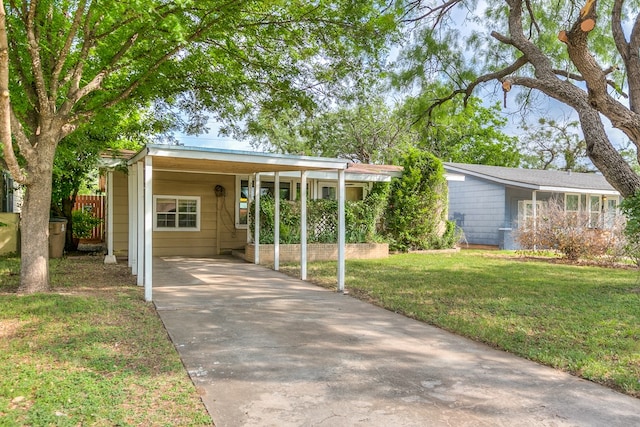 single story home with an attached carport, fence, a front yard, and concrete driveway