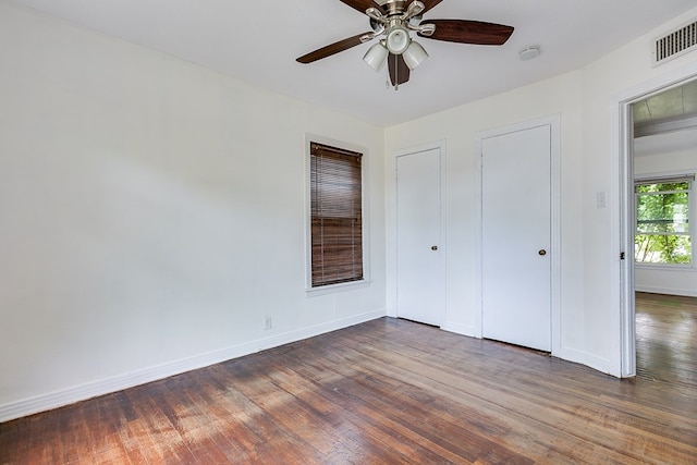 unfurnished bedroom with visible vents, a ceiling fan, baseboards, and wood finished floors