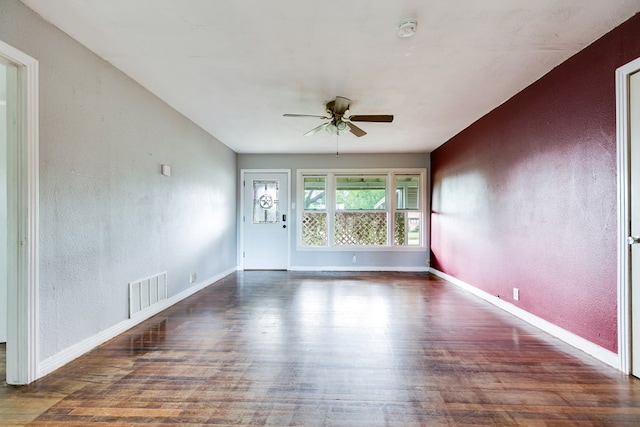 empty room featuring ceiling fan, visible vents, wood finished floors, baseboards, and a textured wall