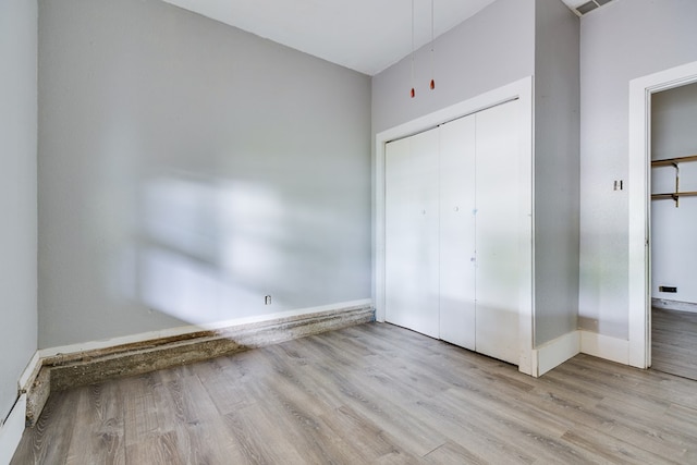 unfurnished bedroom featuring baseboards, a closet, and wood finished floors