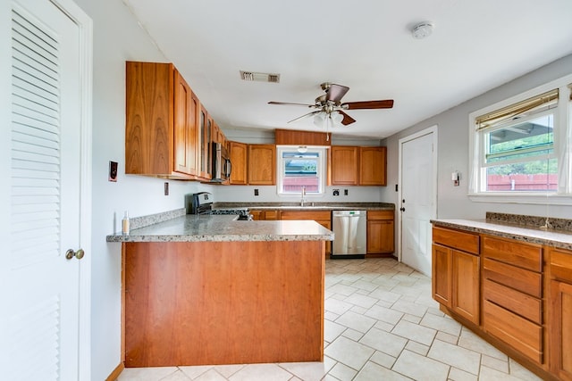 kitchen featuring ceiling fan, appliances with stainless steel finishes, a sink, brown cabinetry, and visible vents