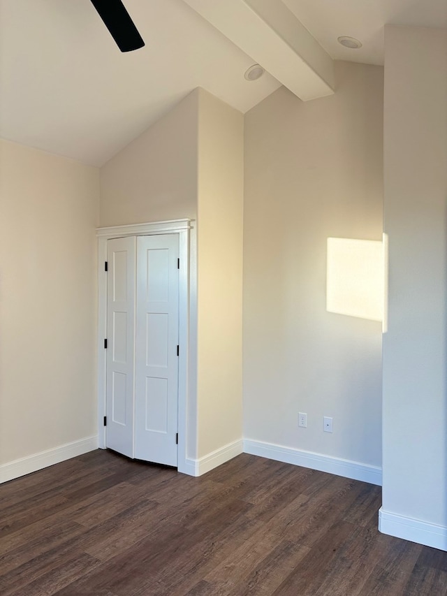 interior space with lofted ceiling with beams, dark wood-style floors, and baseboards