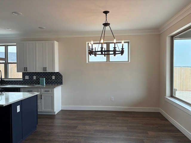 kitchen featuring light stone counters, backsplash, and crown molding