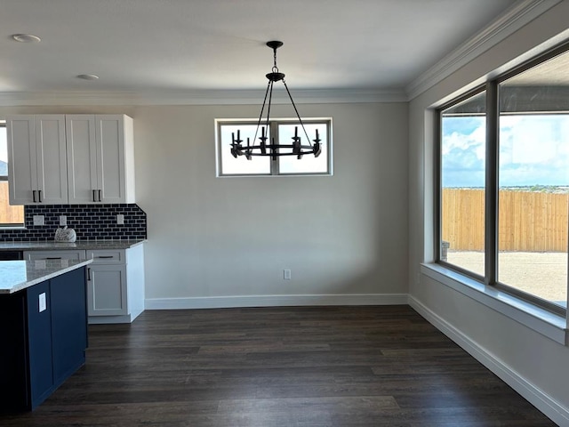 kitchen featuring tasteful backsplash, white cabinets, hanging light fixtures, ornamental molding, and light stone counters