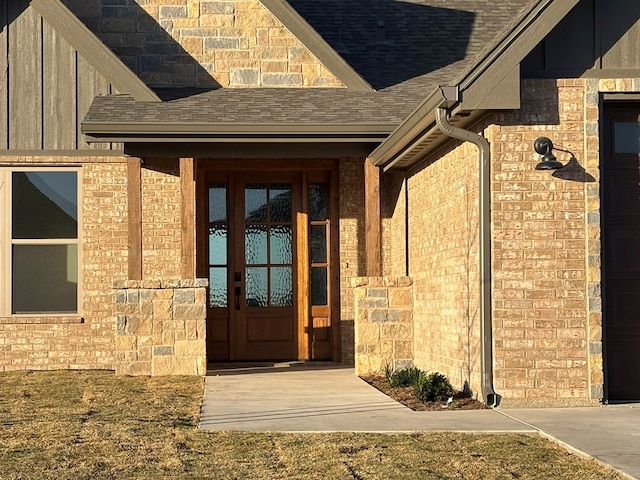 entrance to property featuring a garage, brick siding, and a shingled roof