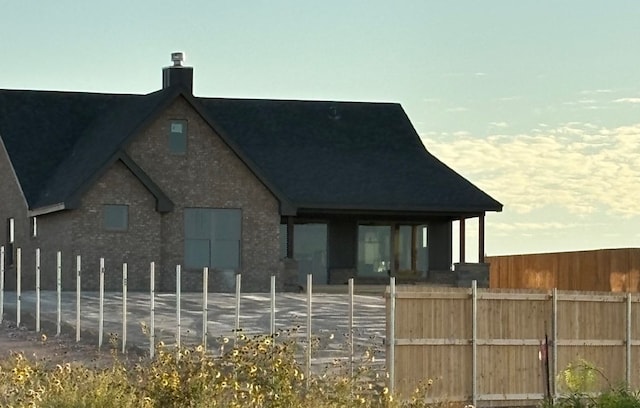 exterior space with brick siding, a chimney, and fence