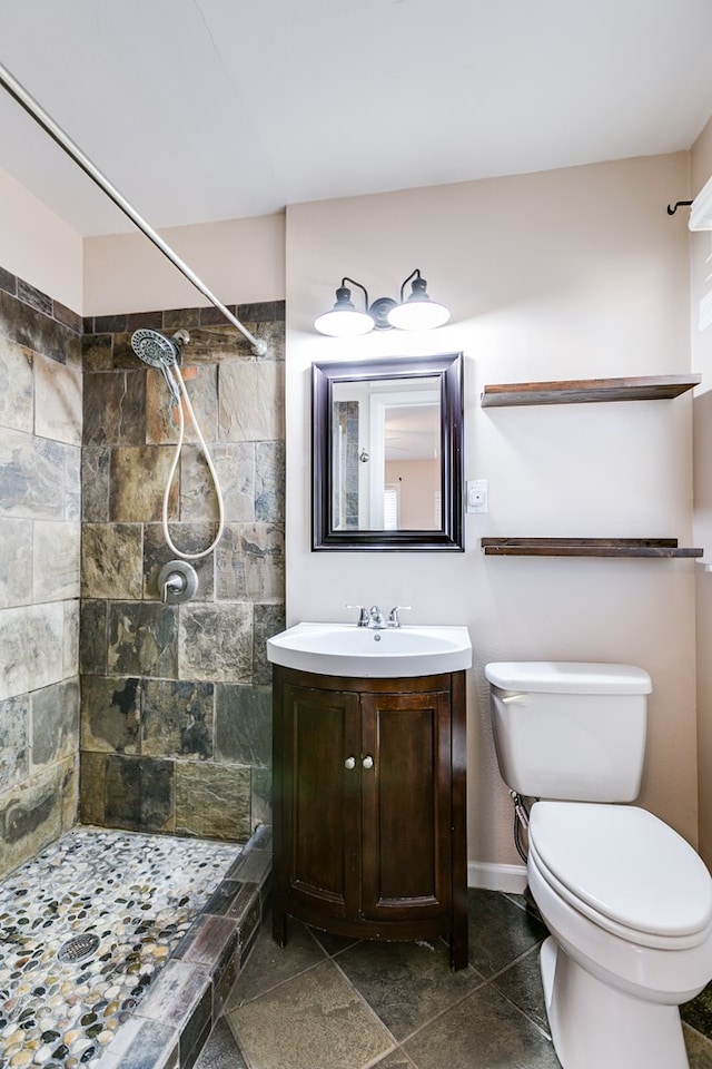 bathroom with vanity, toilet, and a tile shower