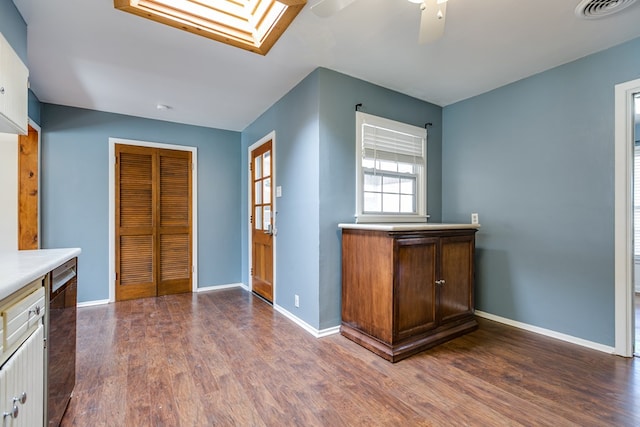 interior space with dark wood-type flooring, ceiling fan, and a skylight