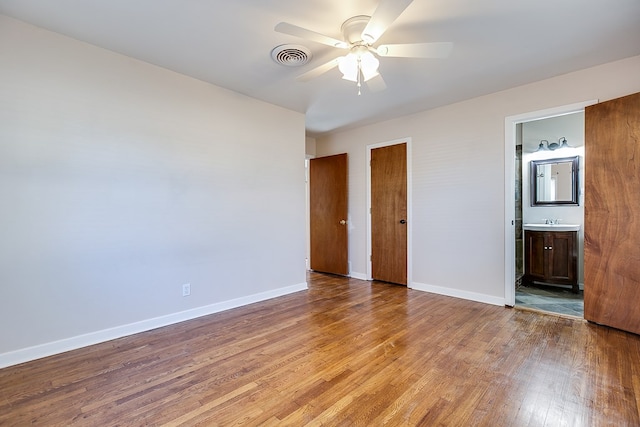 unfurnished bedroom featuring connected bathroom, light hardwood / wood-style floors, sink, and ceiling fan