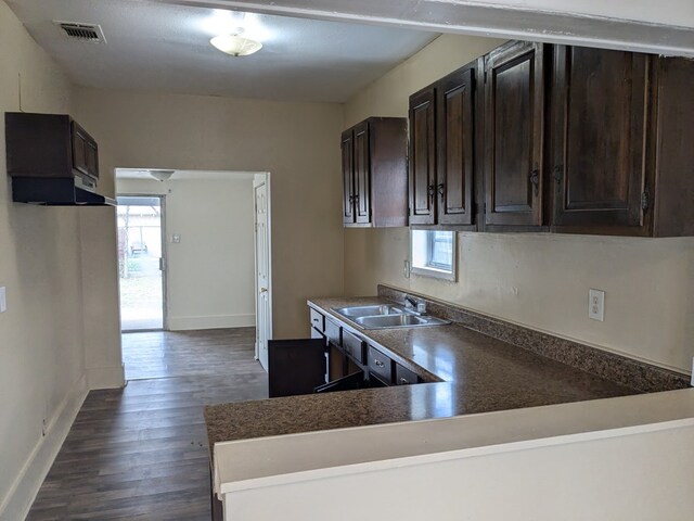 kitchen with dark brown cabinetry, sink, dark hardwood / wood-style flooring, and kitchen peninsula