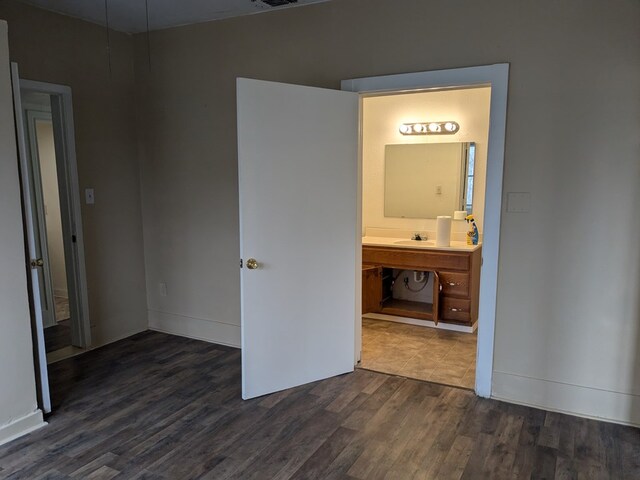 unfurnished bedroom with dark hardwood / wood-style flooring, sink, and ensuite bath