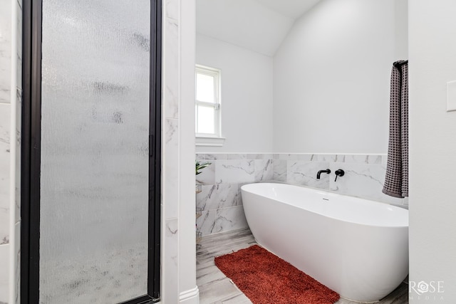 2846 Ricks Dr, San Angelo, TX 76905 - full bath with a stall shower, tile walls, a freestanding bath, vaulted ceiling, and a wainscoted wall