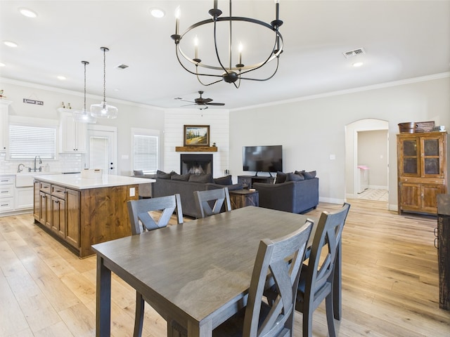 8353 Chad Rd, San Angelo, TX 76957 - dining room featuring arched walkways, a fireplace, ceiling fan, a chandelier, and ornamental molding