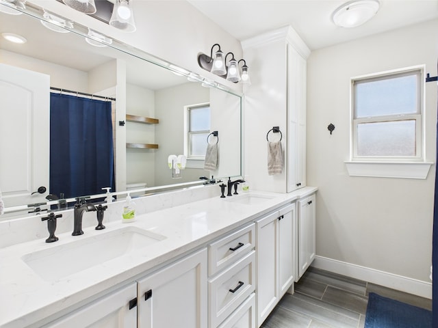 8353 Chad Rd, San Angelo, TX 76957 - full bathroom featuring baseboards, double vanity, toilet, and wood finished floors