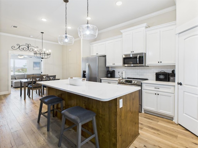8353 Chad Rd, San Angelo, TX 76957 - kitchen with stainless steel appliances, ornamental molding, a kitchen island, a kitchen breakfast bar, and white cabinets