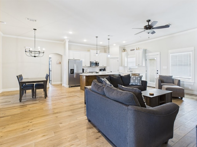8353 Chad Rd, San Angelo, TX 76957 - living room with a chandelier, ceiling fan, light wood-style floors, arched walkways, and baseboards
