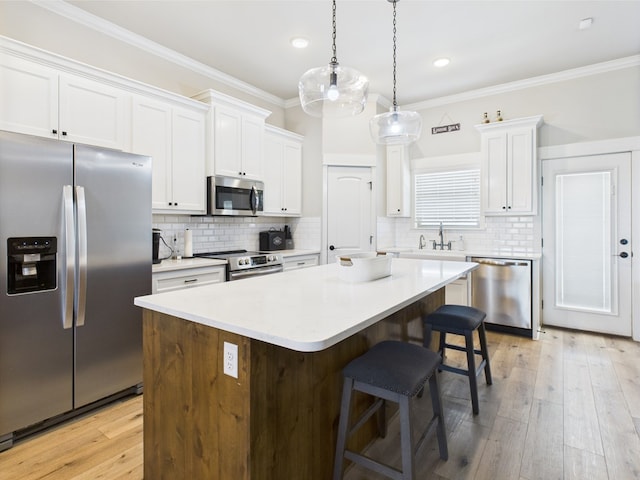 8353 Chad Rd, San Angelo, TX 76957 - kitchen with appliances with stainless steel finishes, a center island, a breakfast bar area, white cabinetry, and crown molding