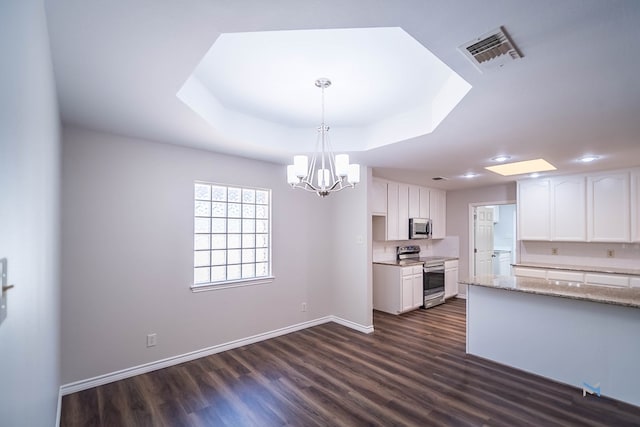 kitchen with dark hardwood / wood-style floors, a tray ceiling, pendant lighting, stainless steel appliances, and white cabinets