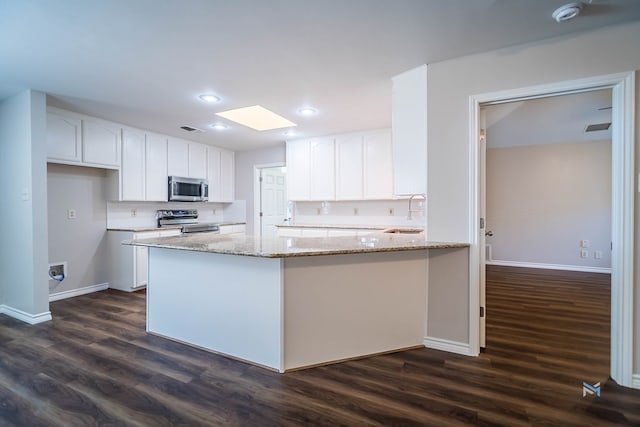 kitchen with stainless steel appliances, light stone countertops, white cabinets, and dark hardwood / wood-style flooring