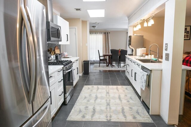 kitchen featuring white cabinetry, appliances with stainless steel finishes, dark tile patterned flooring, and sink