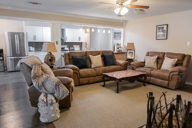 living room with dark wood-type flooring, ceiling fan, ornamental molding, and sink