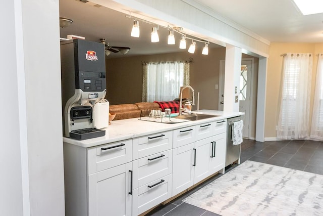 kitchen with sink, ceiling fan, white cabinets, dark tile patterned flooring, and stainless steel dishwasher