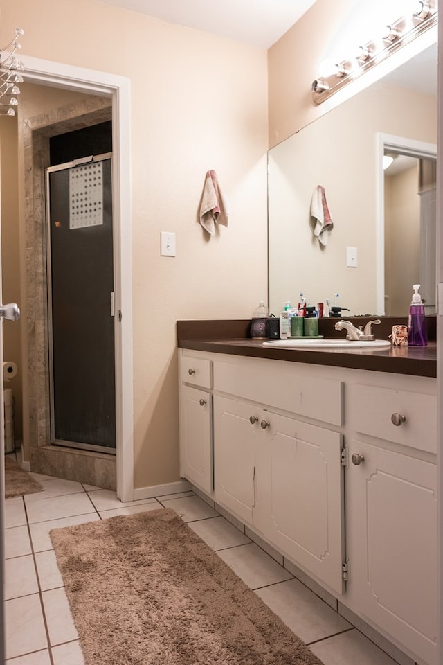 bathroom featuring vanity, a shower with shower door, and tile patterned floors