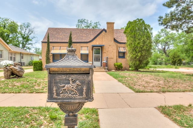 english style home featuring a chimney and a shingled roof