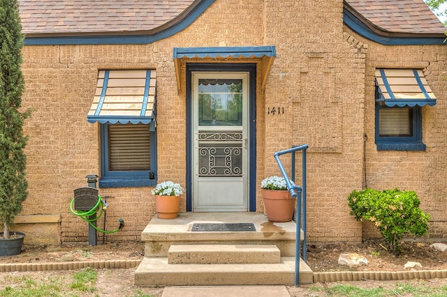 entrance to property featuring a shingled roof