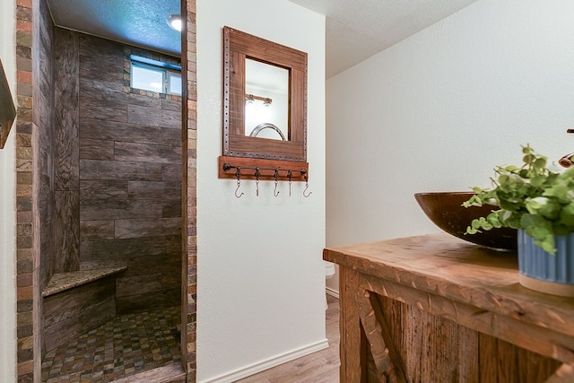 bathroom featuring a walk in shower, wood finished floors, toilet, and baseboards